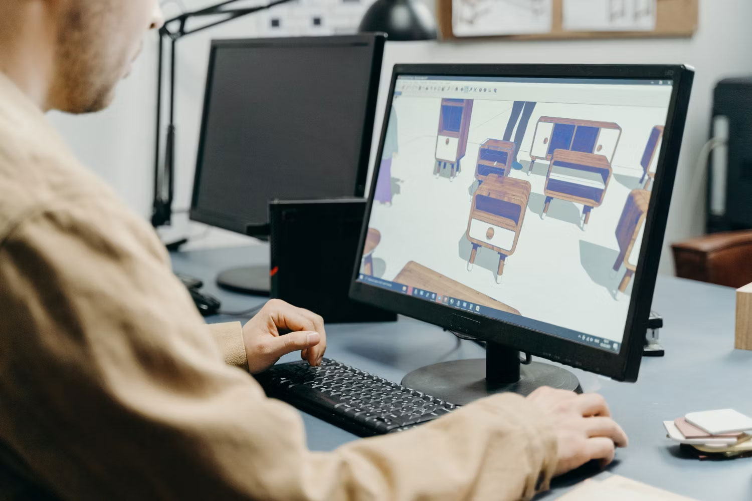 Nhà thiết kế ngồi trước máy tính, làm việc trên mô hình nội thất 3D